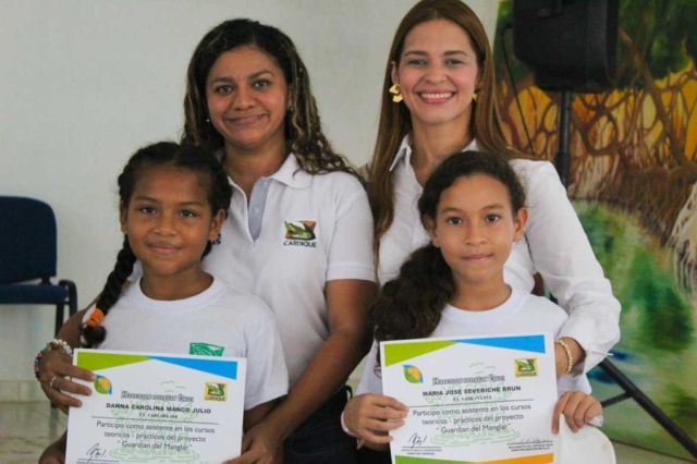 Dory Luz Jimenez Ingeniera del área de gestión ambiental de Cardique, Isabel Mathieu, directora social de la fundación, entregando certificados a Dana Manco Julio y a Maria José Severiche de la I.E. de Tierra Baja.