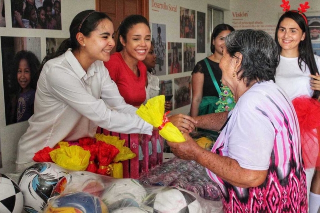 Isabel Torres del programa de Adulto Mayor recibe su regalo de navidad junto a voluntarios de Novus Civtias.